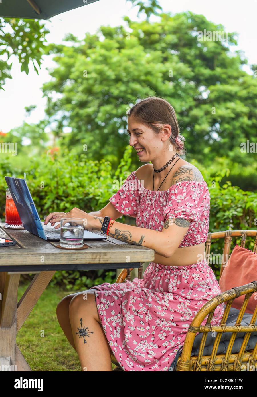 Cute videographer and vlogger taking a video with camera and tripod in summer garden Stock Photo