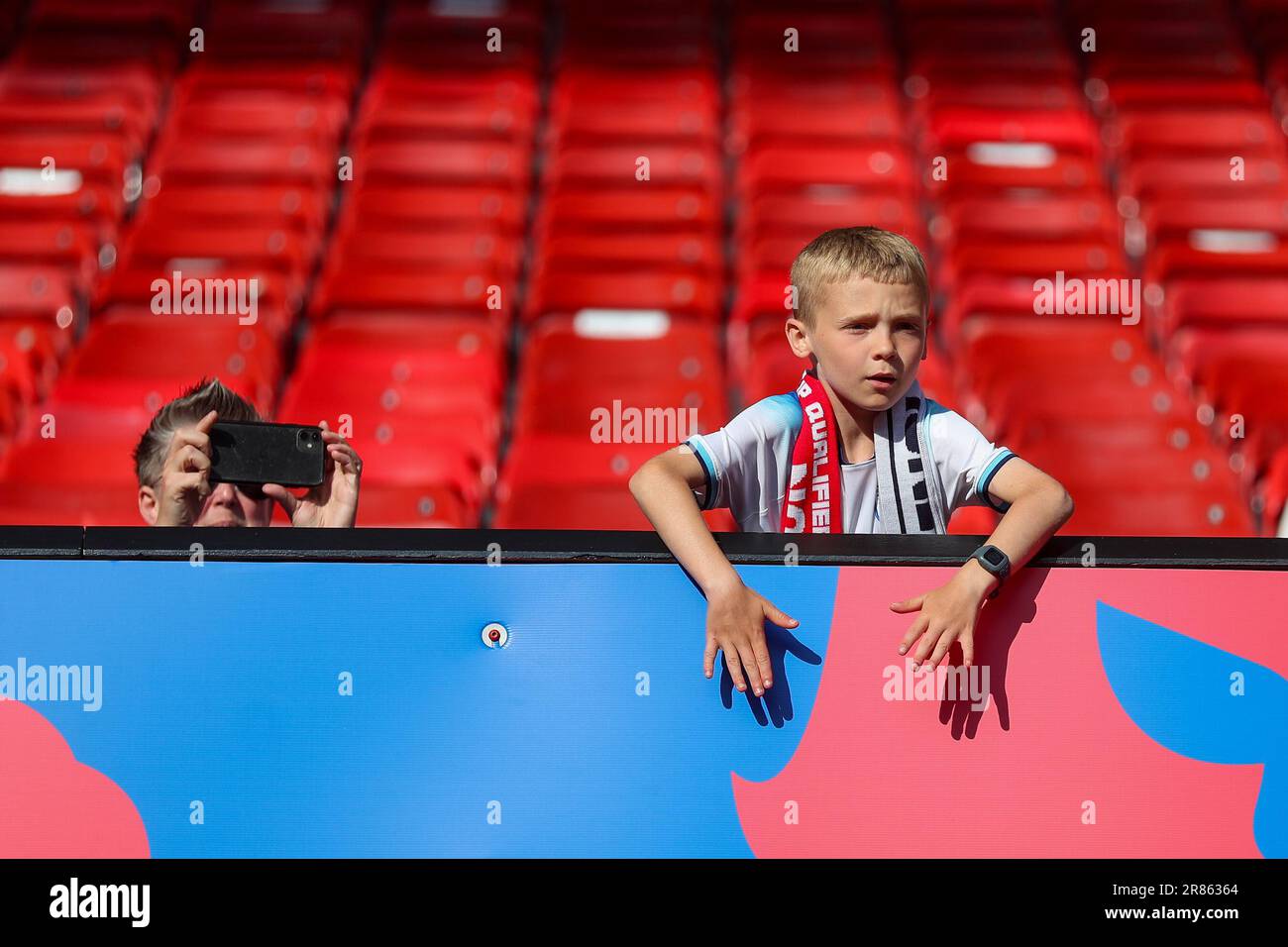 Manchester, UK. 19th June, 2023. A young England supporter takes in the atmosphere as his friend takes his picture *** during the 2024 UEFA EURO Qualifiers match between England and North Macedonia at Old Trafford, Manchester, England on 19 June 2023. Photo by Simon Hall. Editorial use only, license required for commercial use. No use in betting, games or a single club/league/player publications. Credit: UK Sports Pics Ltd/Alamy Live News Stock Photo
