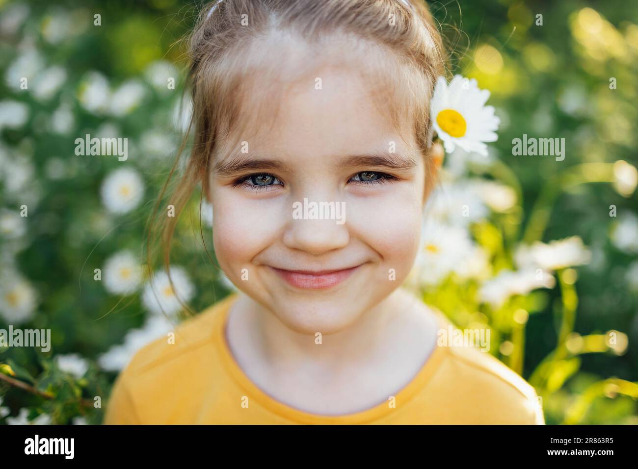 Child portrait of cute little blue-eyed girl with flower of chamomile ...