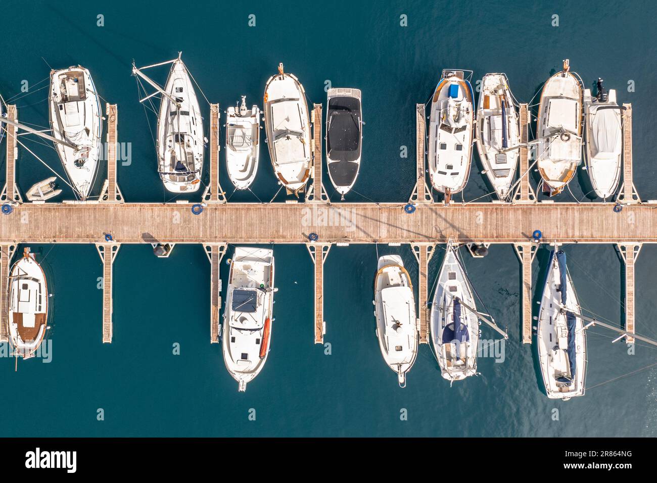 Yachts, sailboats and motorboats in a marina in Spain. On turquoise blue water of the Mediteranian sea. Aerial view seen from above. Stock Photo