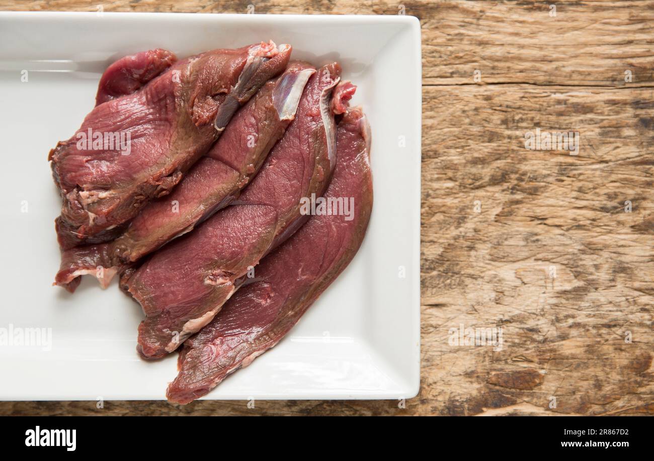 Raw venison slices from a wild roe deer, Capreolus capreolus, that are being prepared to be homecooked in a black bean sauce. England UK GB Stock Photo