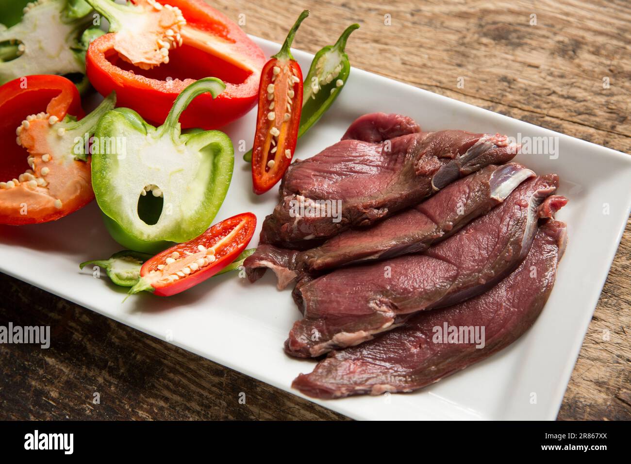 Raw venison slices from a wild roe deer, Capreolus capreolus, that are being prepared to be homecooked in a black bean sauce. England UK GB Stock Photo