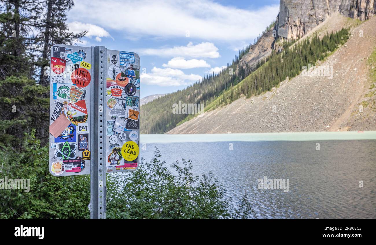 Signpost on shores of Lake Louise covered with stickers from around the world in Banff National Park, Alberta, Canada on 6 June 2023 Stock Photo