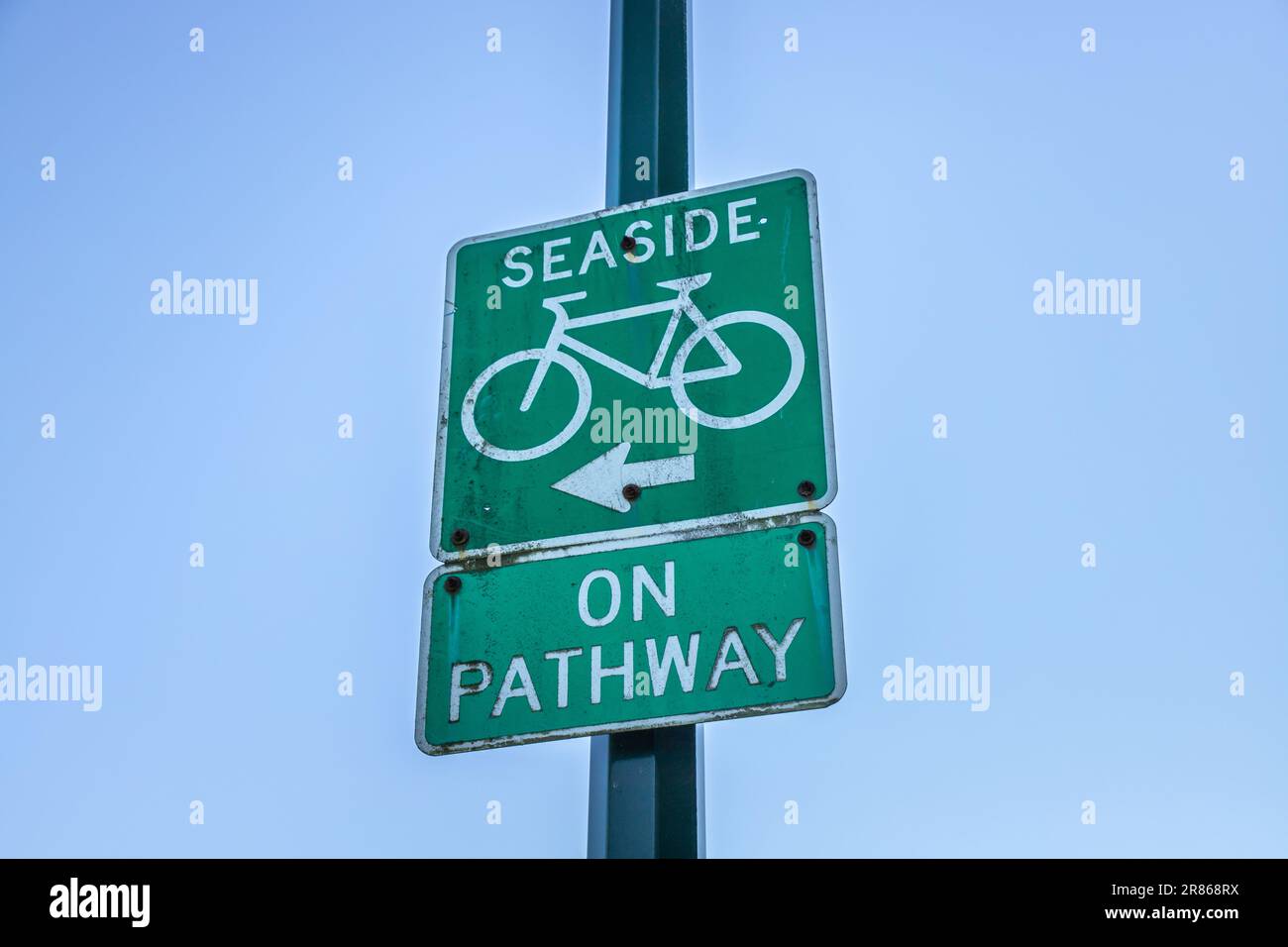 A road sign “SEASIDE ON PATHWAY” with icons of bicycle and arrow direction sign. Rustic countryside road near beach, summer journey concept Stock Photo