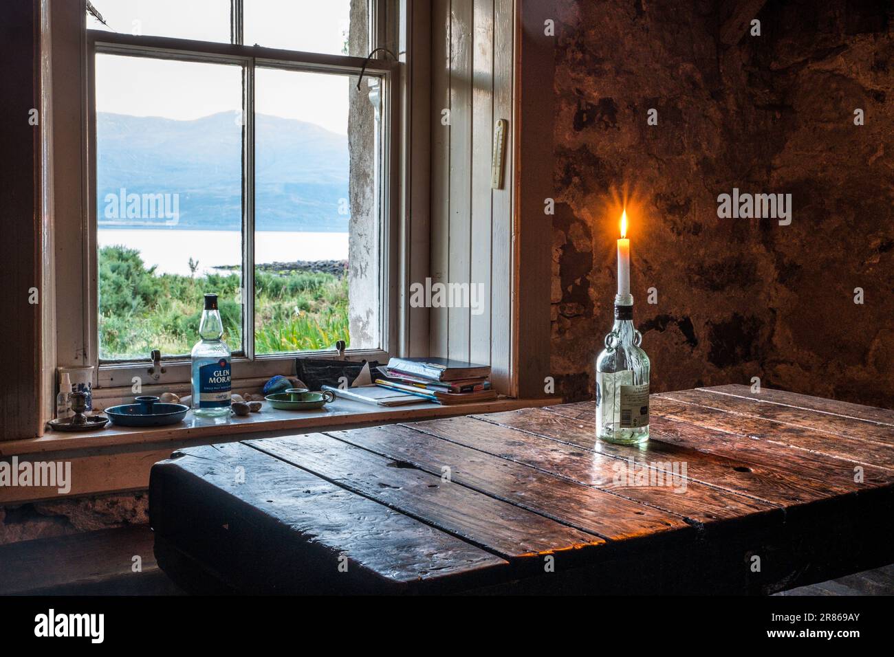 A candle in a bottle in an old stone cottage Stock Photo