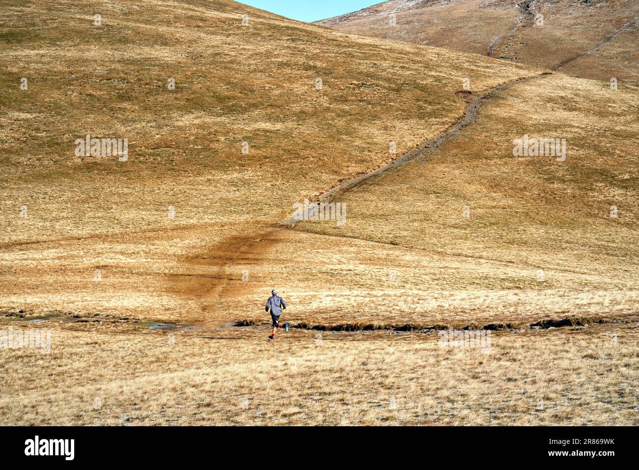 A fell runner at Coledale Hause below Sand Hill in winter in the English Lake District, UK. Stock Photo