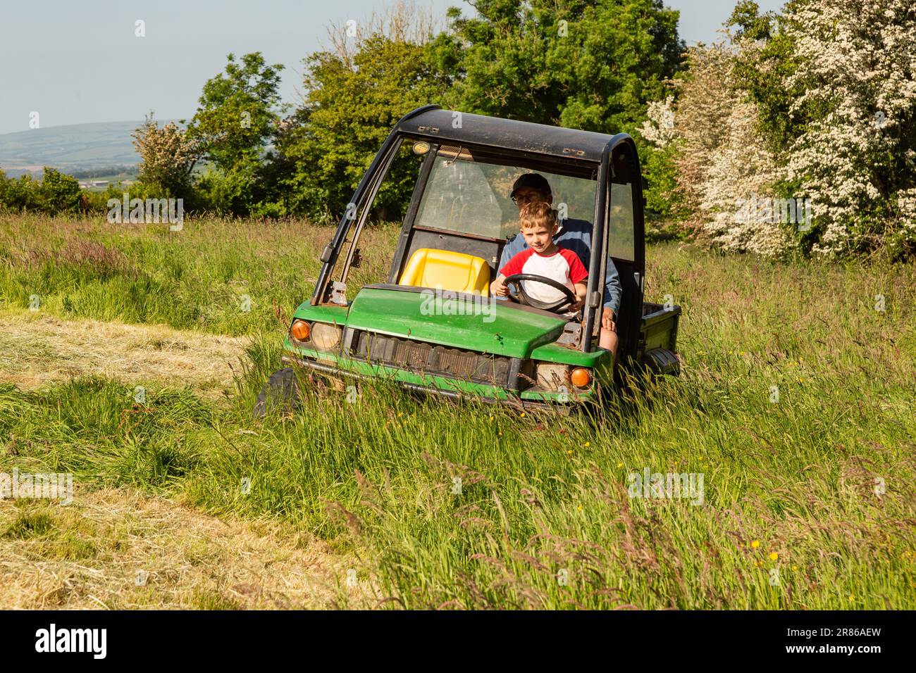 Six year old boy learning to dive a John Deere Gator, High Bickington, North Devon, England