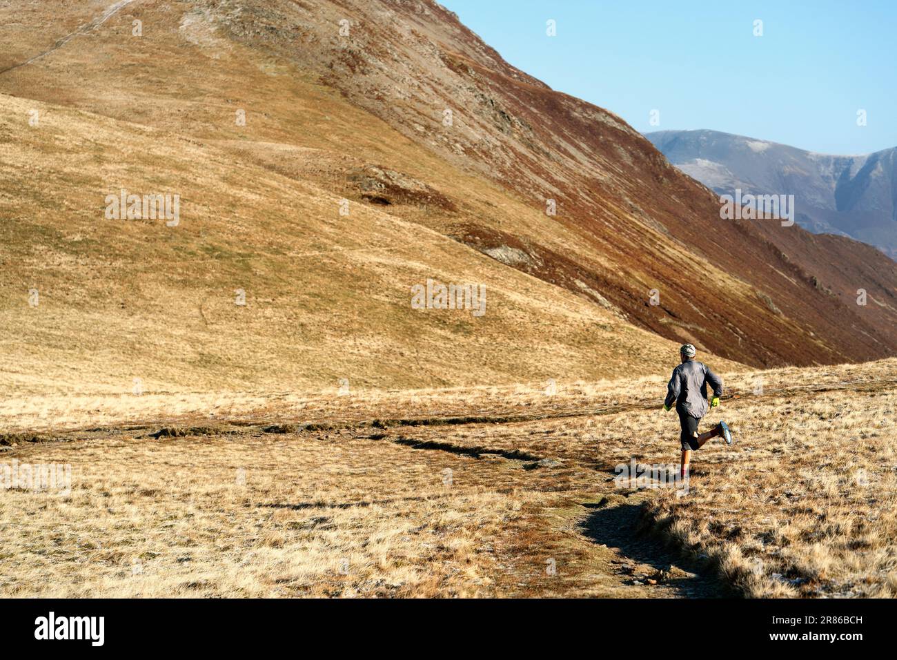 A fell runner at Coledale Hause below Sand Hill in winter in the English Lake District, UK. Stock Photo