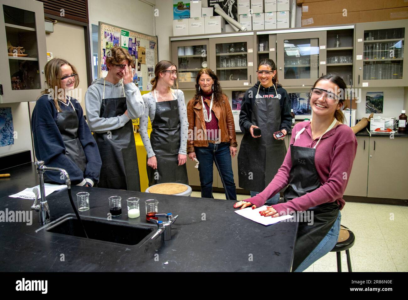 A high school chemistry teacher in San Clemente, CA, center, socializes with her Advanced Placement (AP) students in aprons and safety glasses. Note b Stock Photo