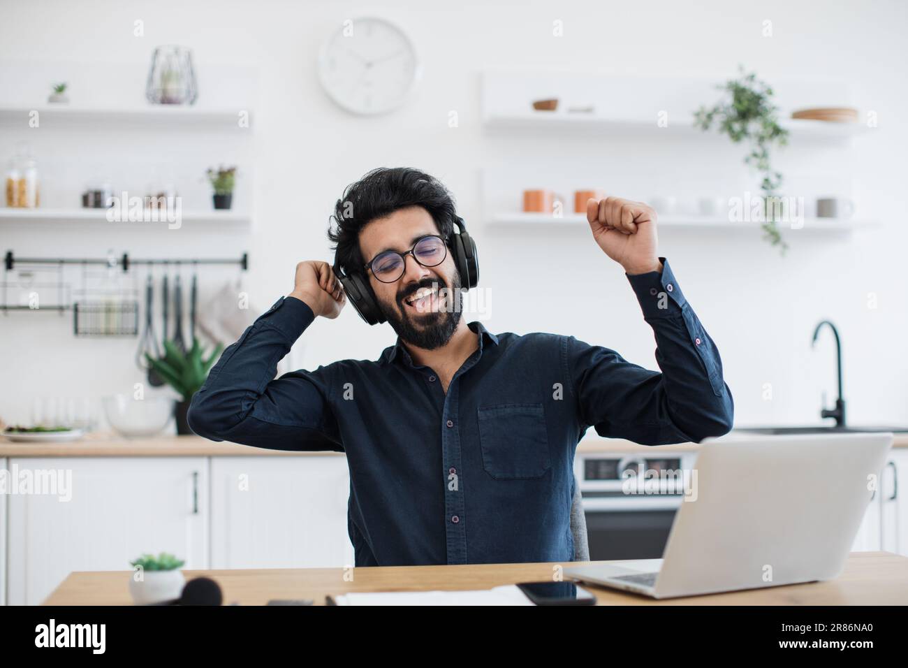 Emotional mature adult with raised fists listening to favourite songs ...