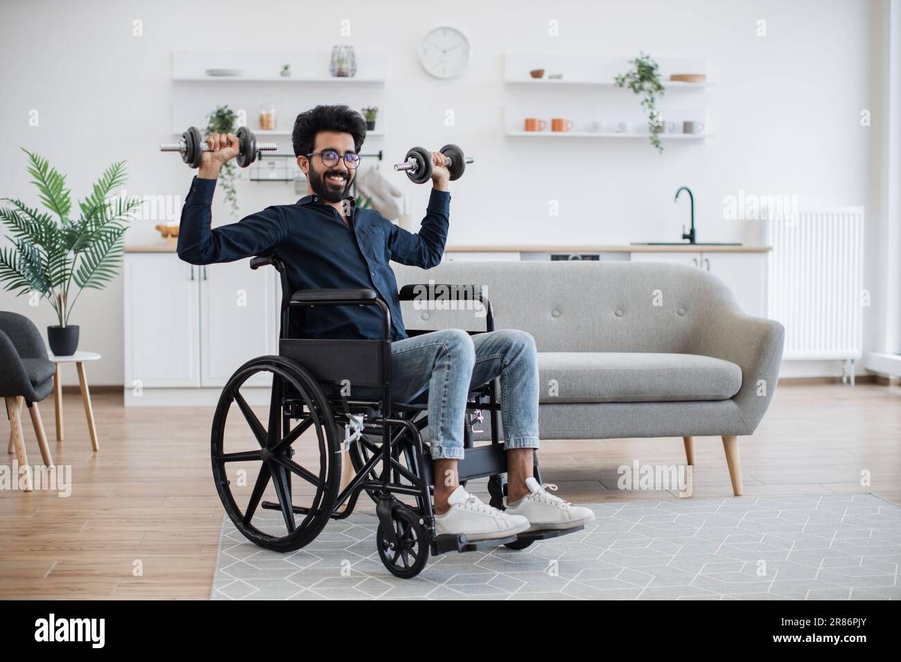 https://c8.alamy.com/comp/2R86PJY/full-length-view-of-handsome-indian-man-in-wheelchair-lifting-weights-while-exercising-with-limited-mobility-indoors-smiling-adult-using-moderate-intensity-activity-during-home-workout-in-kitchen-2R86PJY.jpg