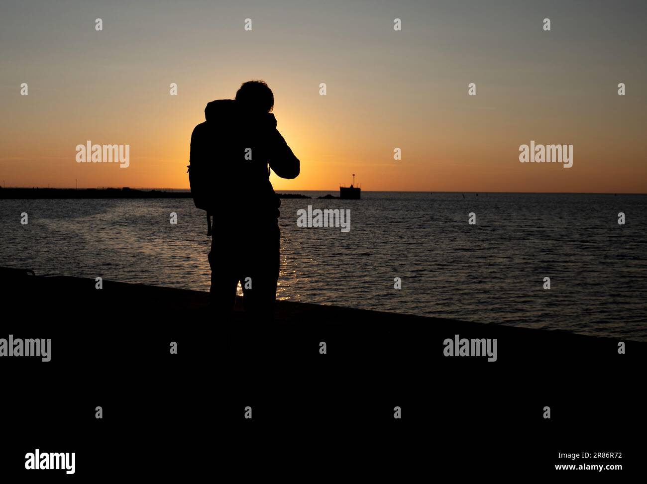 Silhouette of a photographer in action at Malmo harbor during late afternoon Stock Photo