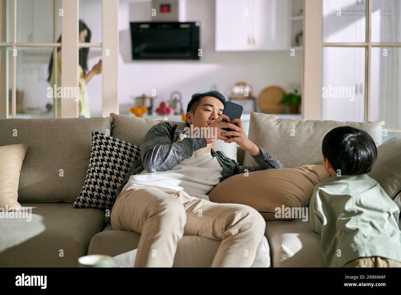 young asian couple parents addicted to smartphones ignoring child, concept for smartphone or social media addiction Stock Photo