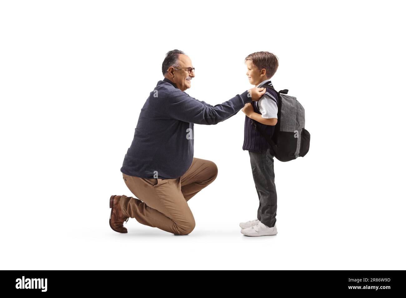 Full length profile shot of a grandfather helping a boy getting ready for school isolated on white background Stock Photo