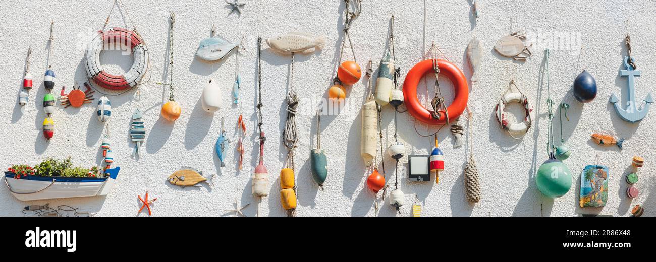 Nautical themed fishing gear, artifacts and decoration from the sea on a white wash pebbledash wall in the coastal seaside fishing village of Lower La Stock Photo