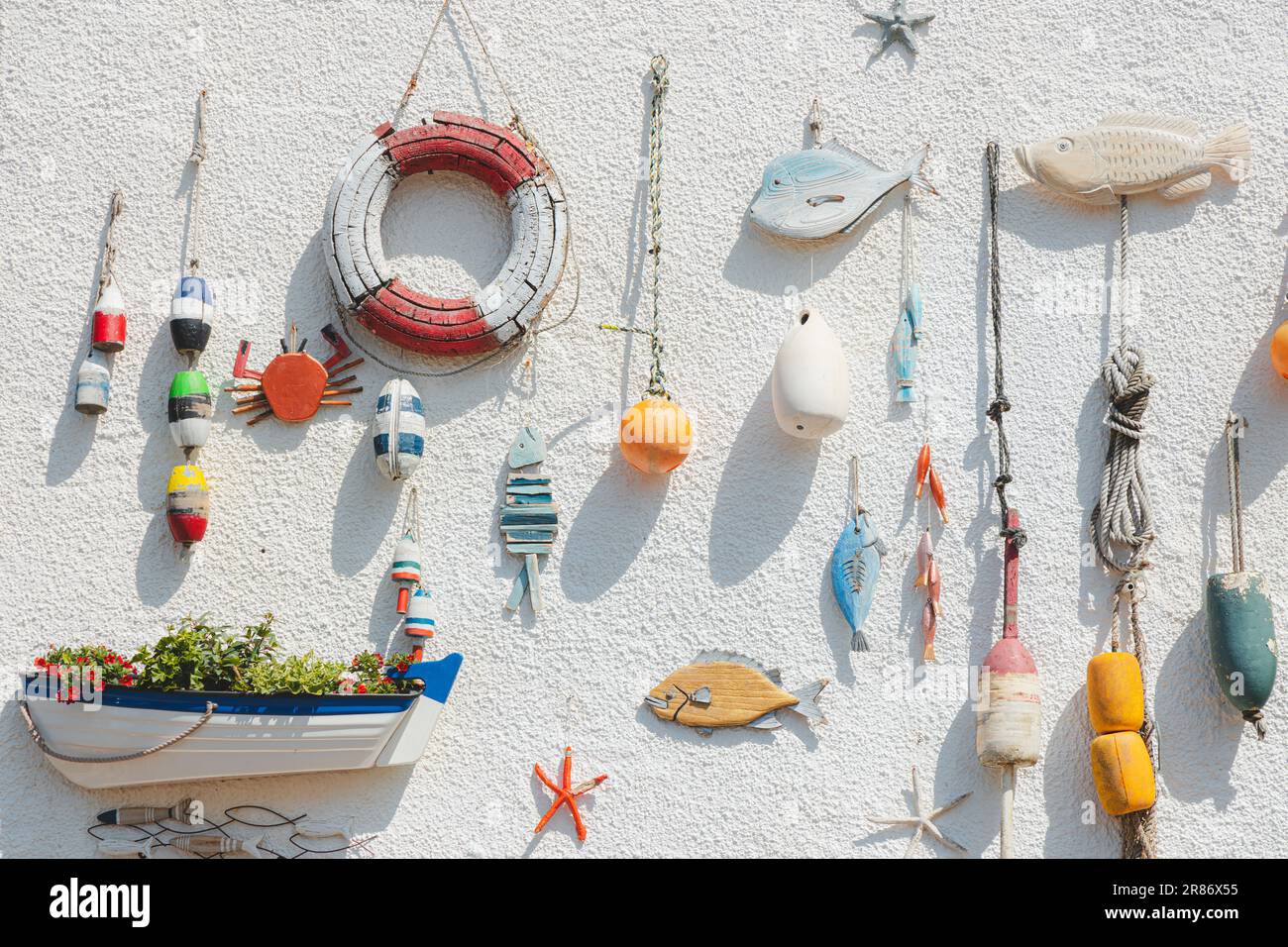 Nautical themed fishing gear, artifacts and decoration from the sea on a white wash pebbledash wall in the coastal seaside fishing village of Lower La Stock Photo