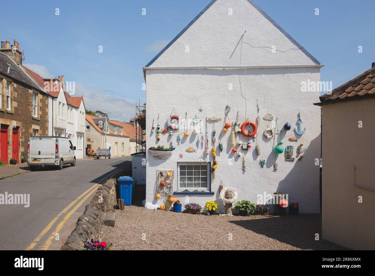 Lower Largo, UK - June 9 2023: Nautical themed fishing gear, artifacts and decoration from the sea on a white wash pebbledash wall in the coastal seas Stock Photo