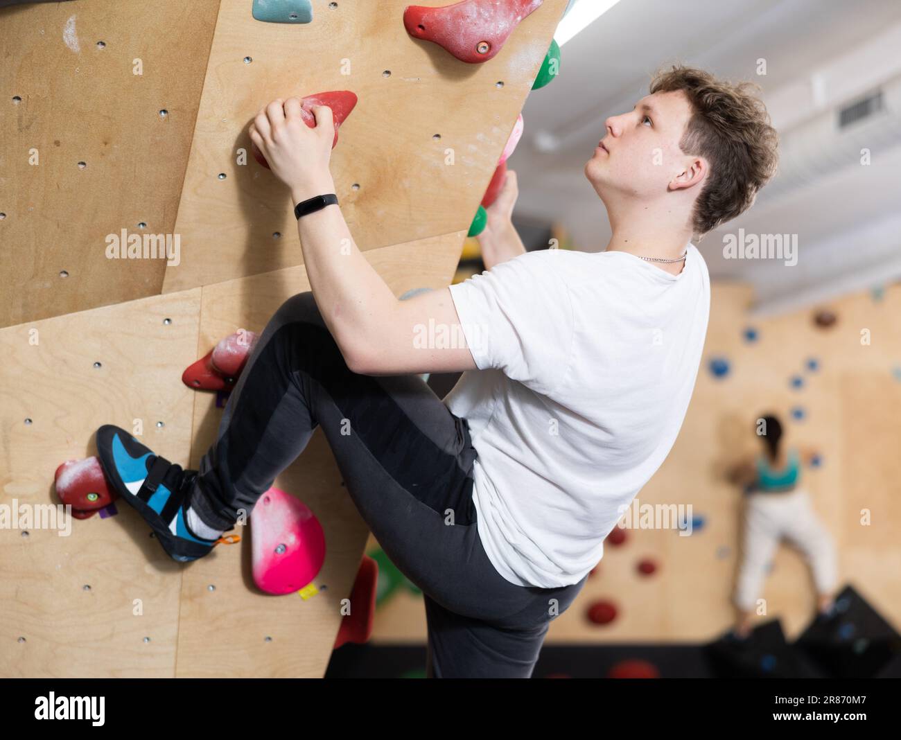 Male mountaineer climbing artificial rock wall without belay indoors