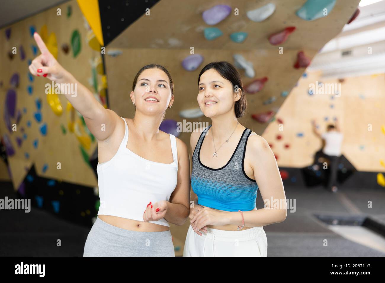Two young women posing against climbing wall Stock Photo - Alamy