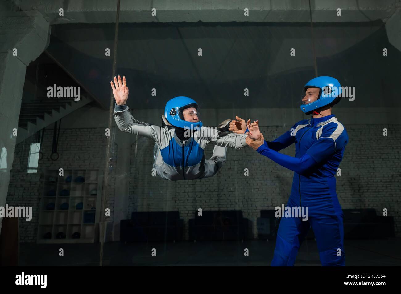 A male instructor teaches a woman how to fly in a wind tunnel. Free ...