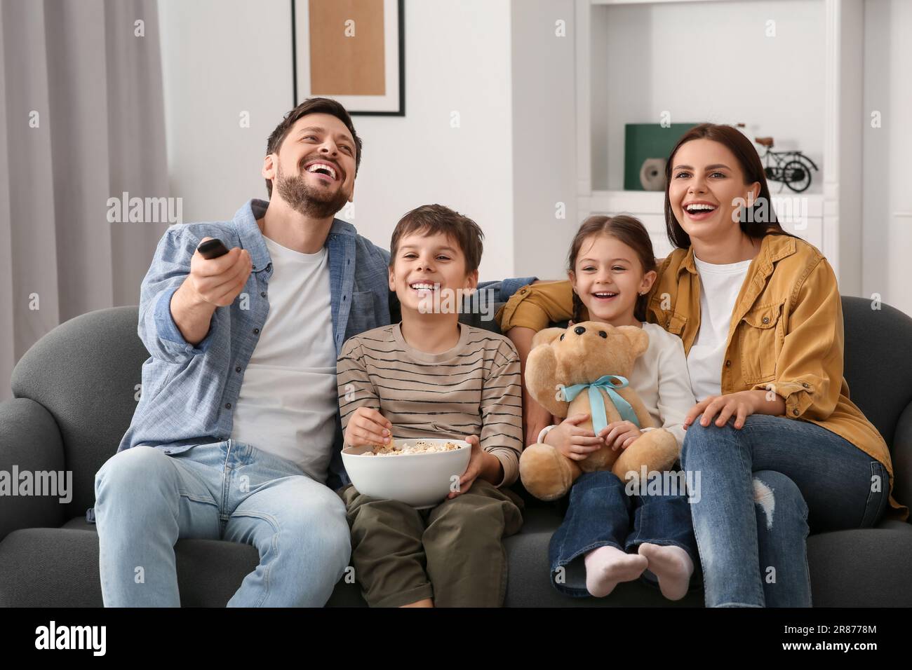 Happy family watching TV at home. Father changing channels with remote ...