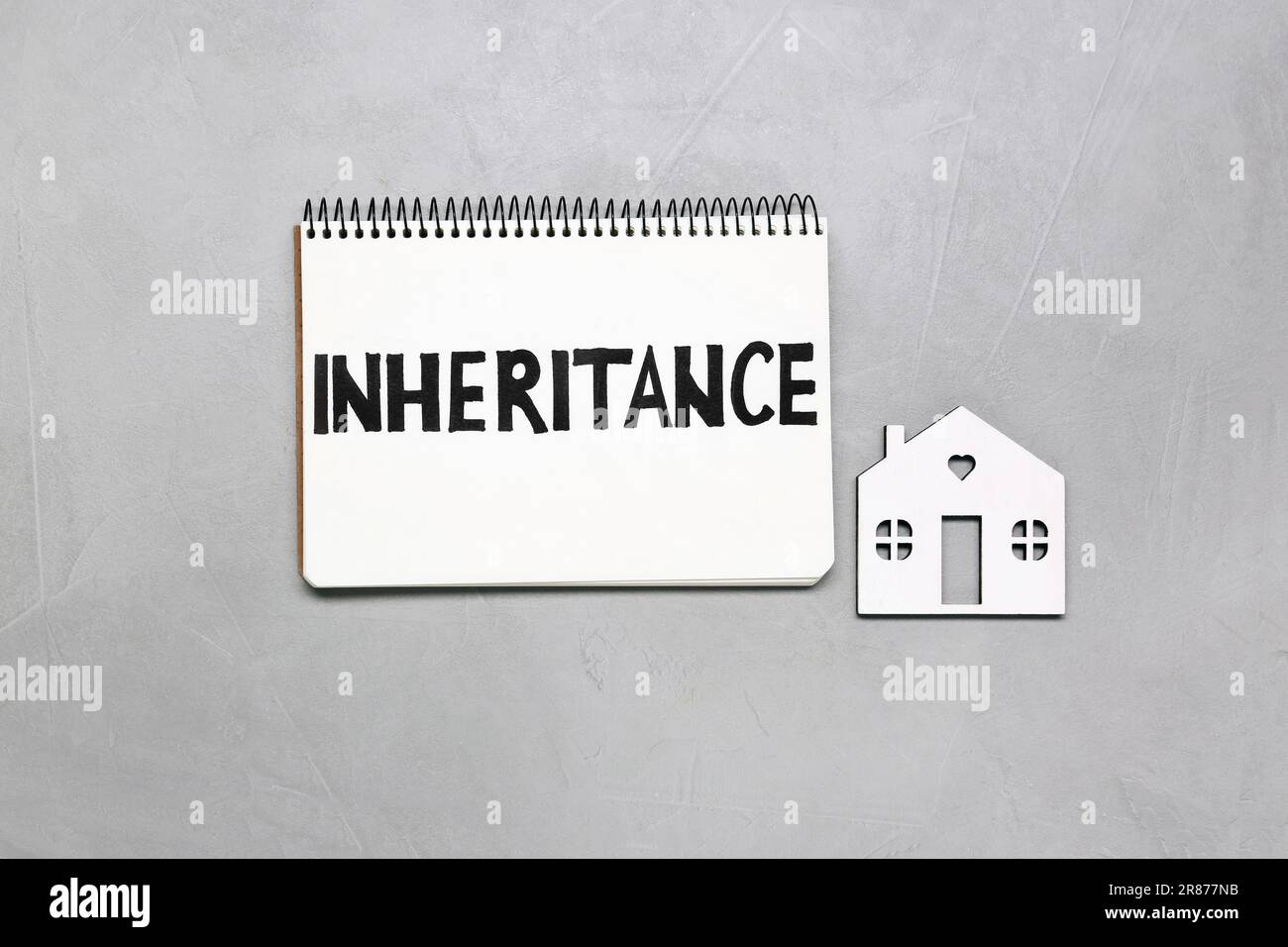 Notebook with word Inheritance and house model on grey background, flat lay Stock Photo
