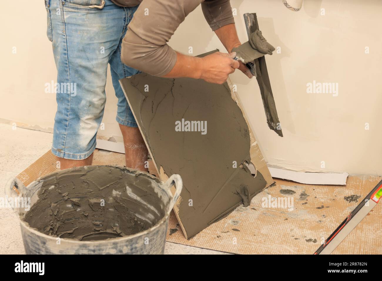 Worker spreading adhesive mix over tile with spatula, closeup Stock ...