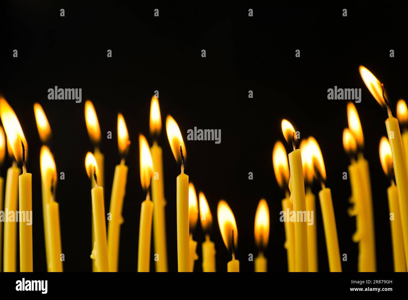 Many burning church candles on black background Stock Photo - Alamy