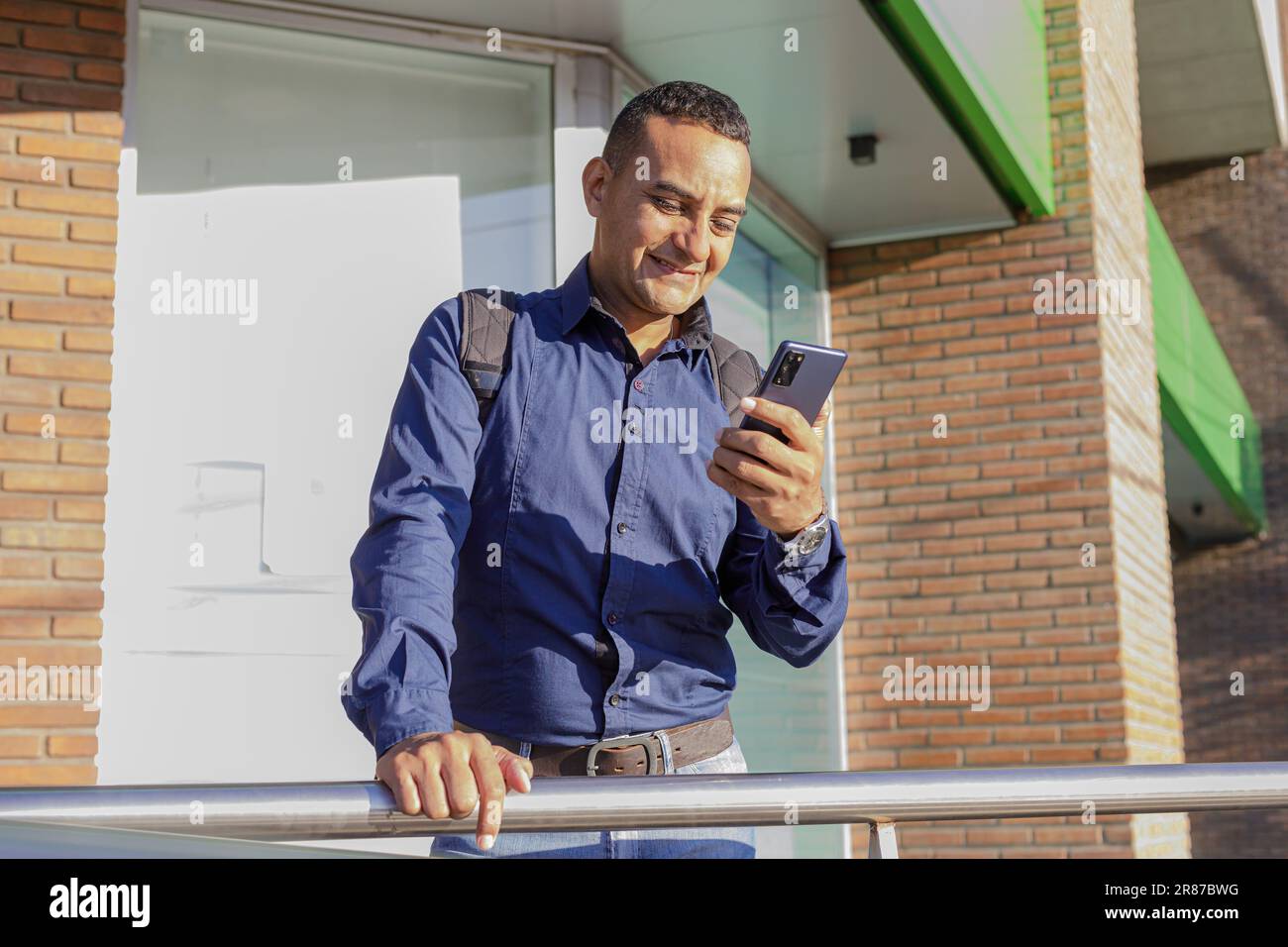 Smiling young latin man looking at his mobile phone. Stock Photo