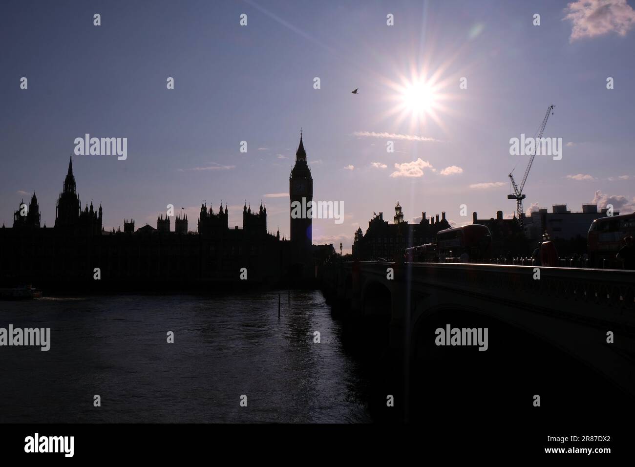 The Houses of Parliament in silhouette with the sun seen in a starburst effect. MPs inside debate and vote on Partygate report late into the evening. Stock Photo
