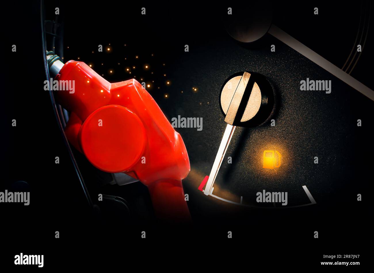 Low fuel indicator, fuel nozzle and gauge on dark background. Stock Photo