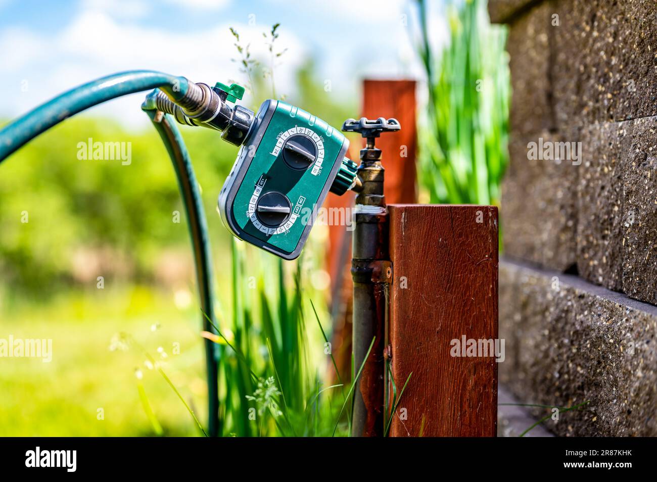 Garden water timer on a spigot with a splitter and hoses Stock Photo