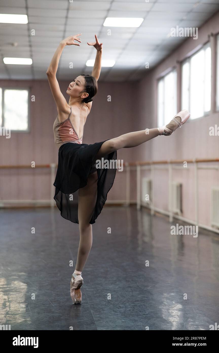 Graceful Asian ballerina in a beige bodysuit and black skirt is ...