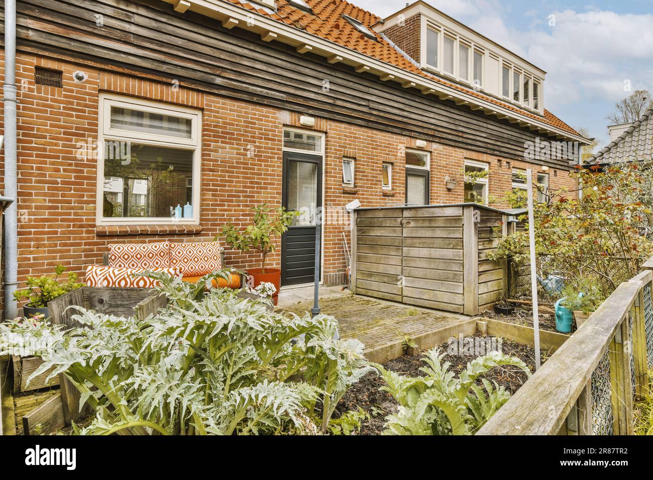 a house with some plants in the front and an outdoor seating area on ...