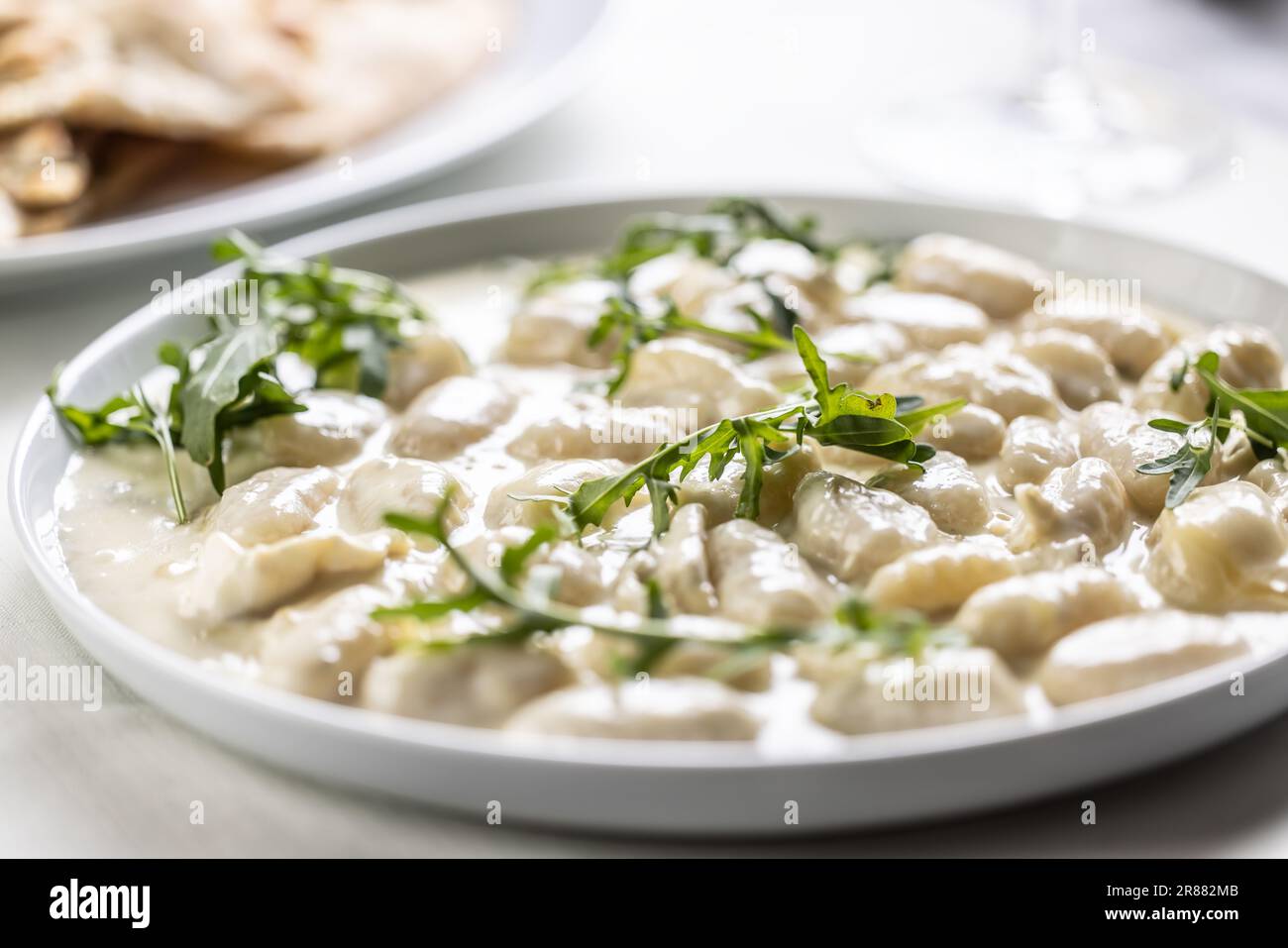 Gnocchi ai quattro formaggi, Italian dough pasta with four types of cheese and ruccola on top. Stock Photo