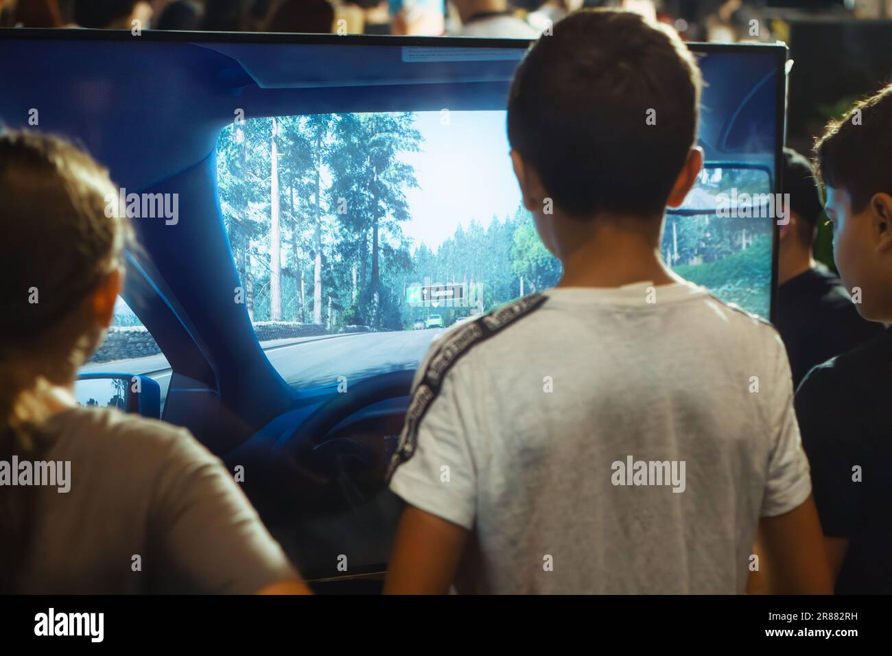 A group of young children playing a racing car computer game displayed on a big digital screen Stock Photo