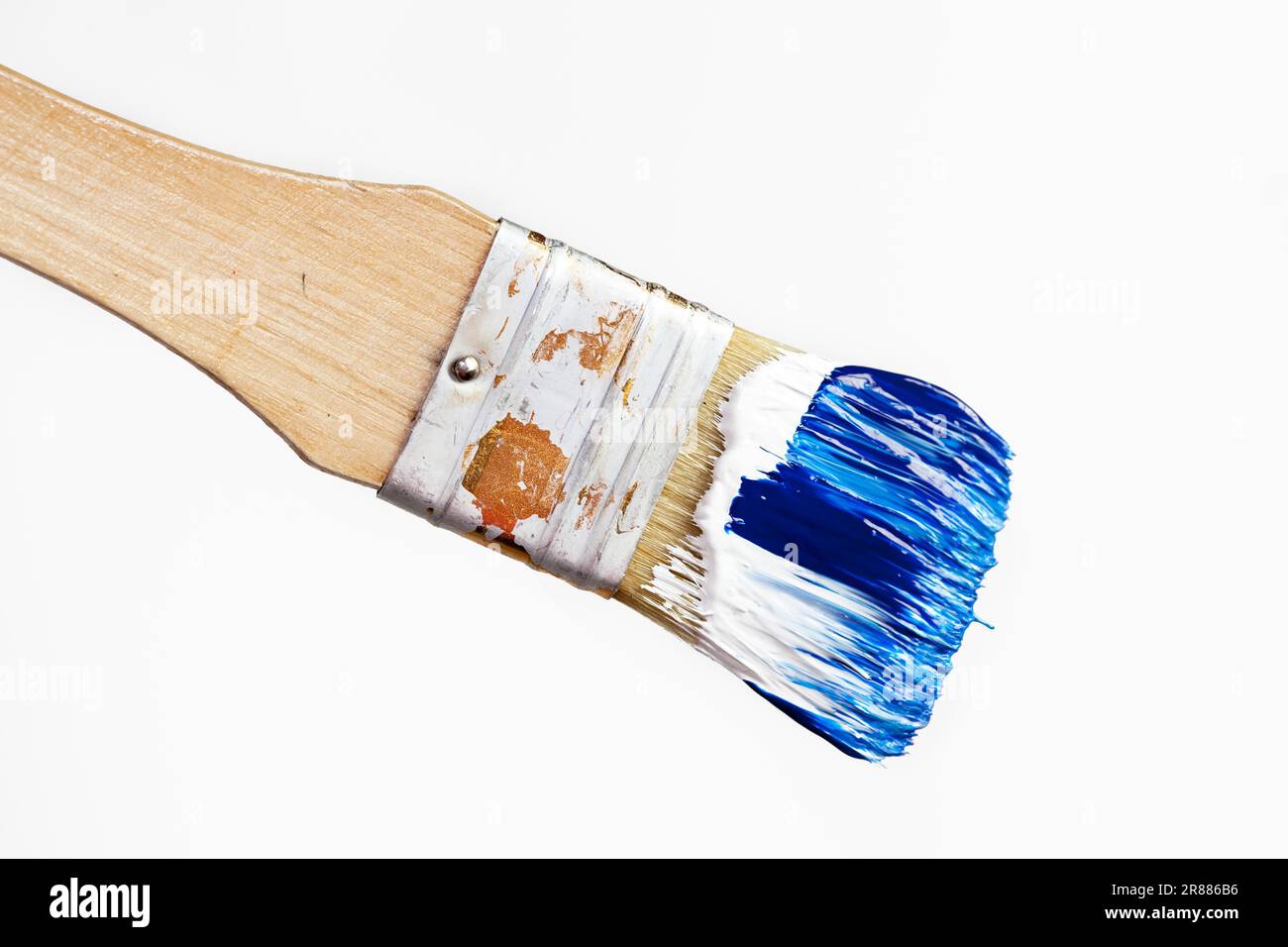 Brush with blue and white acrylic paint against a white background