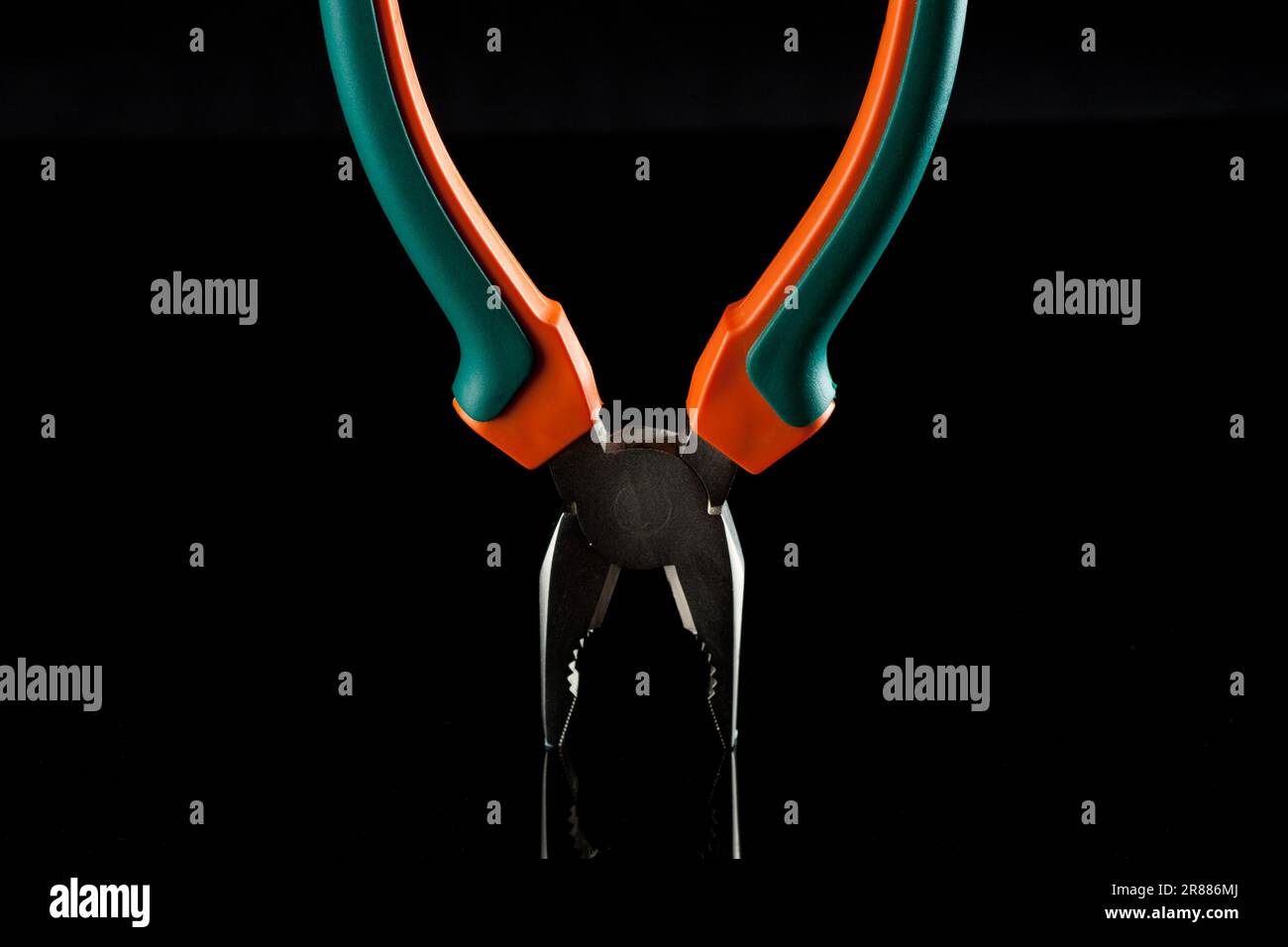 Metal flat-nose pliers with rubbed green and orange grips Stock Photo