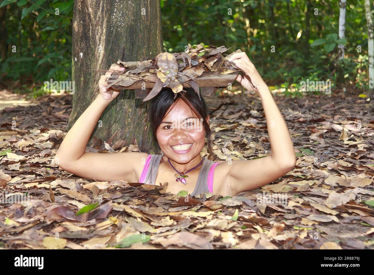 Vietnamese woman showing entrance to tunnel system in Chu Chi, Viet Cong tunnel system, Vietnam Stock Photo