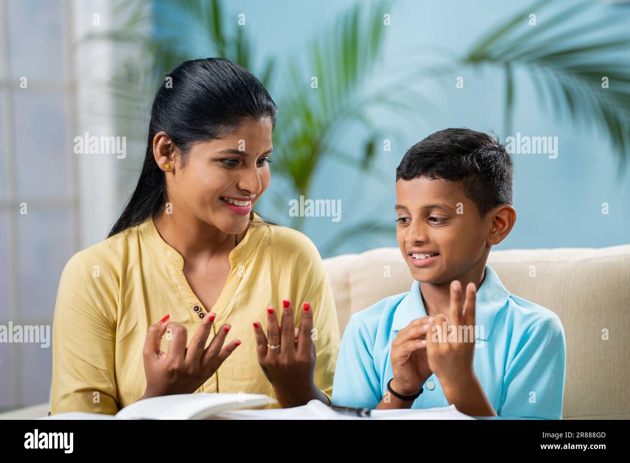 Happy indian mother teaching her son to do maths homework at home - concept of home schooling, tutor and education Stock Photo