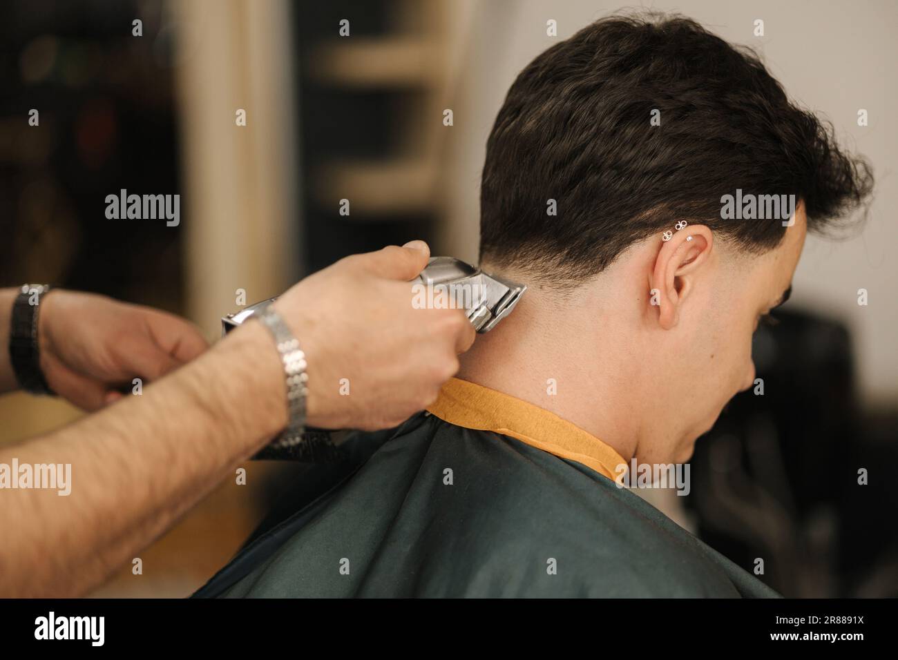 Barber use trimmer to cut hair of man. Back view of male client sitting