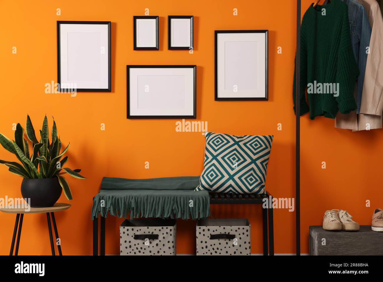 Empty frames hanging on orange wall in stylish room. Mockup for design ...