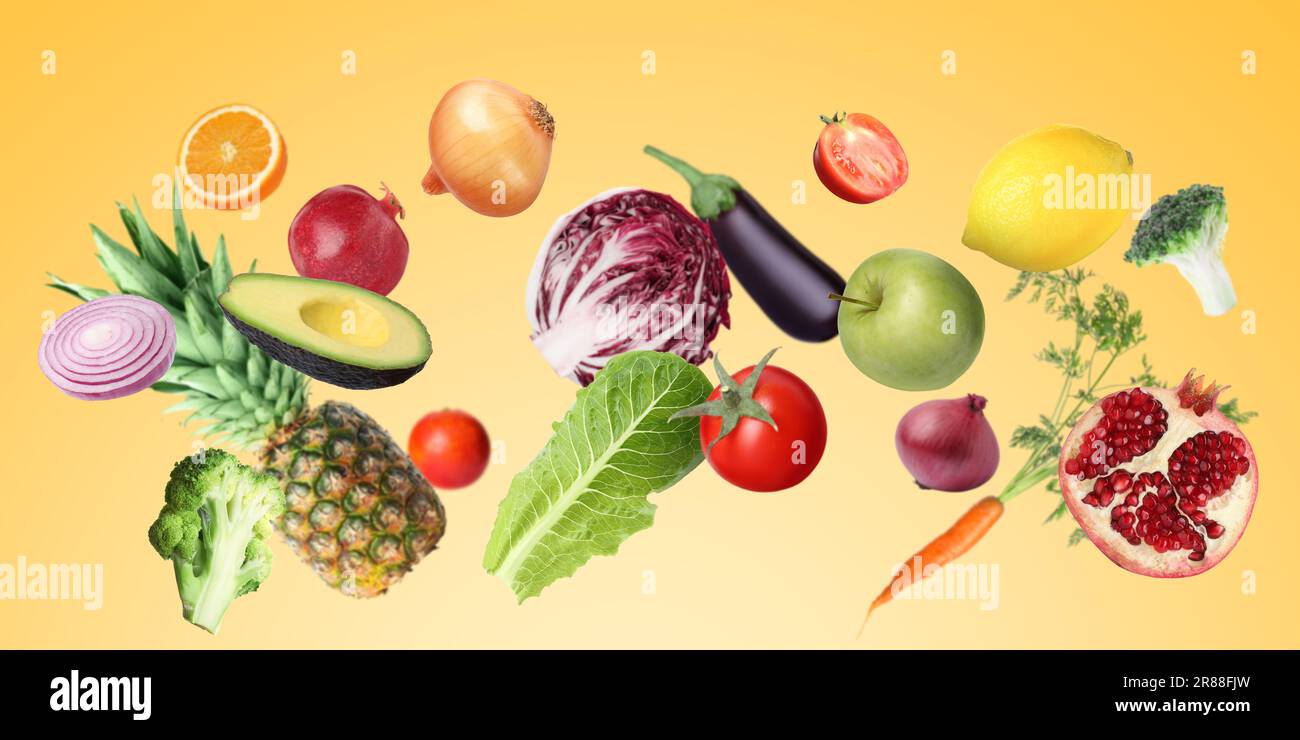 Many fresh vegetables and fruits falling on gold background Stock Photo