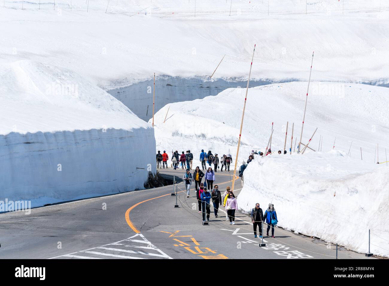 Tateyama, Japan. Tourists walk to and from the snow corridor at Murodo. Murodo is the highest point along the Tateyama Kurobe Alpine Route. Stock Photo