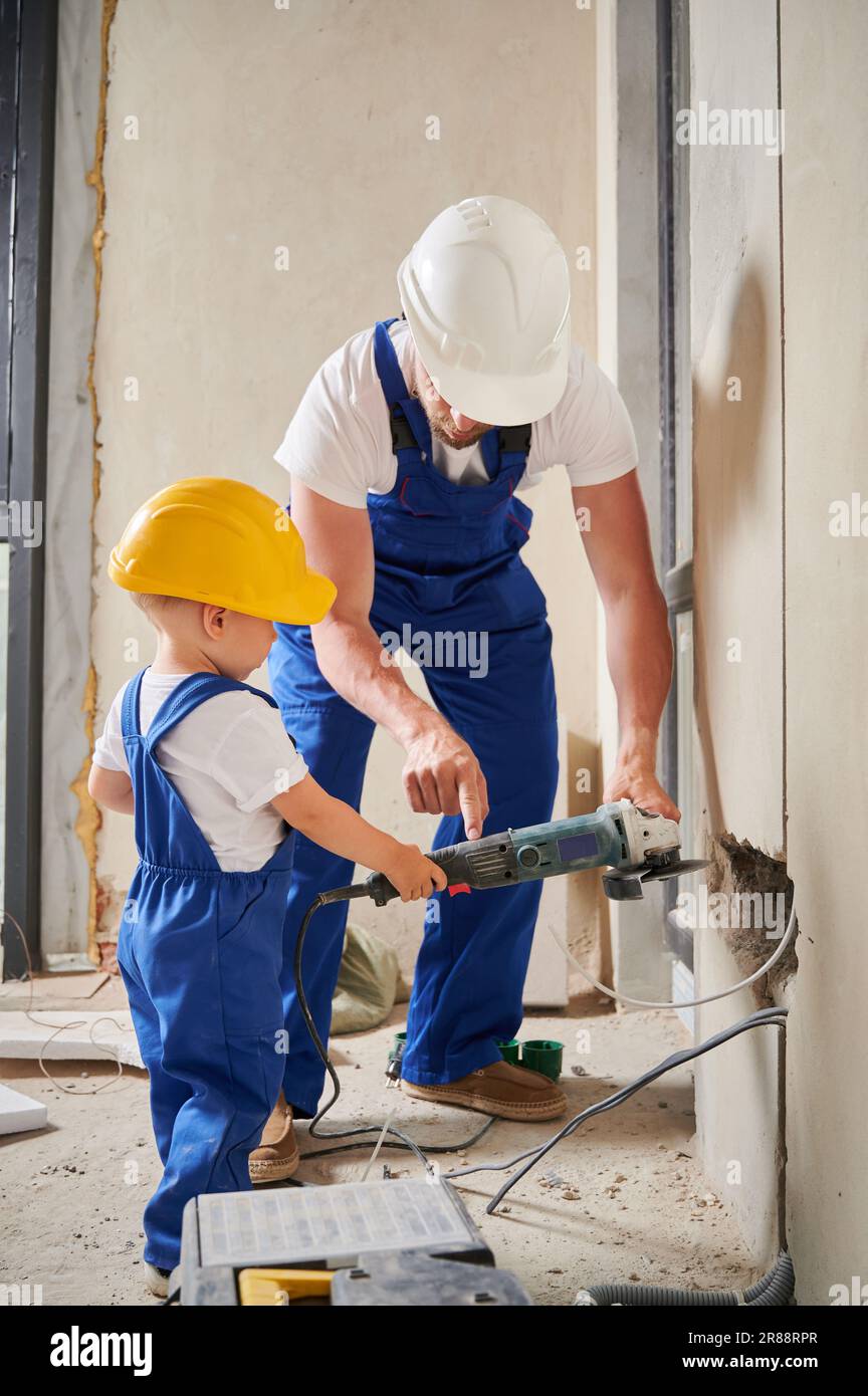 Man and little boy working with electric power tool angle grinder in