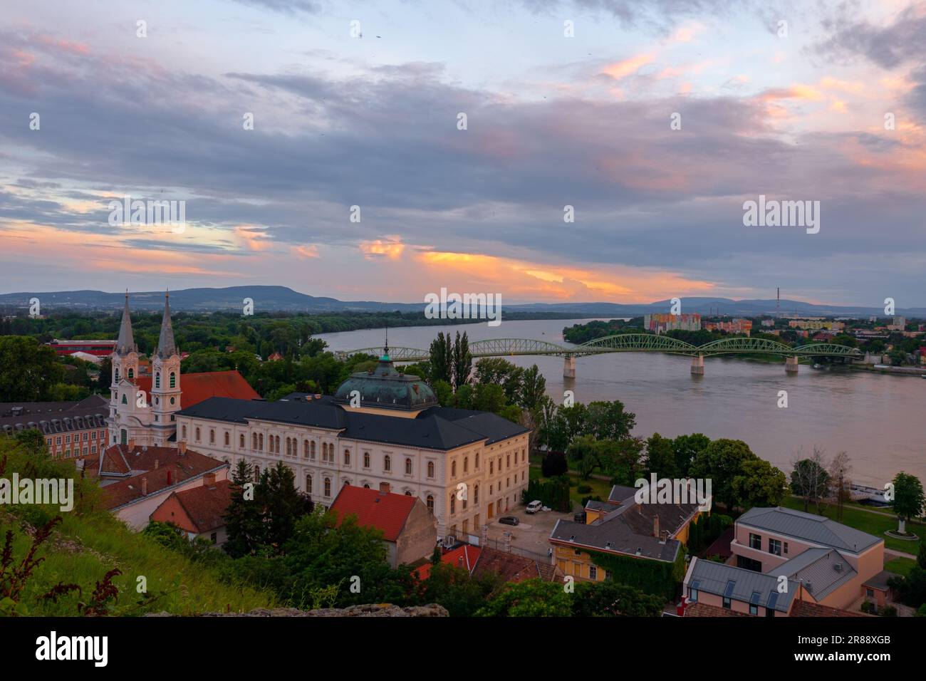 Aerial view about the Archdiocese Office of Esztergom, with Maria Valeria Bridge and Danube at the background. Cloudy sunset. Stock Photo