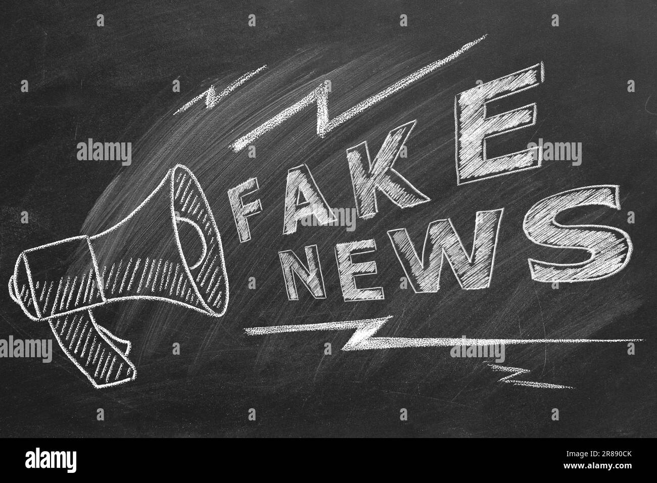 Megaphone with the text FAKE NEWS drawn in chalk on a blackboard. Hand ...