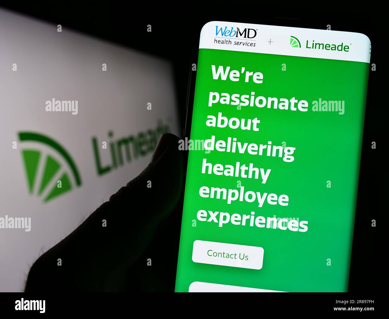 Person holding smartphone with webpage of US employee well-being company Limeade Inc. on screen with logo. Focus on center of phone display. Stock Photo