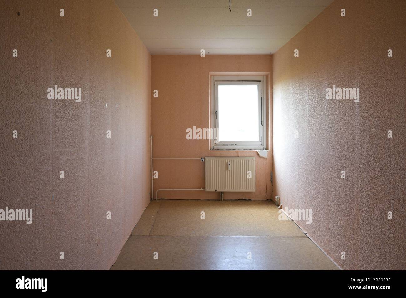 Cramped unrenovated room intended as enough space in a typical rental apartment in social housing with cheap flooring, exposed pipes and poorly insula Stock Photo