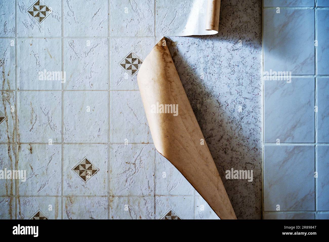 Foil with artificial tiles detaches from the kitchen wall in an old